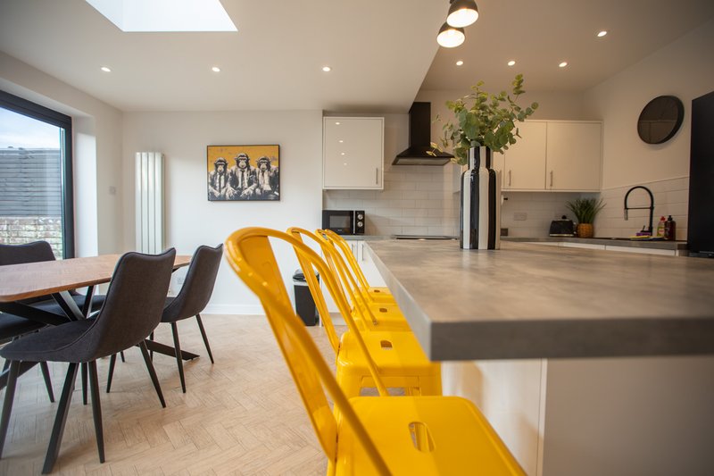 Open-plan kitchen and dining area with yellow chairs, island counter, and modern appliances