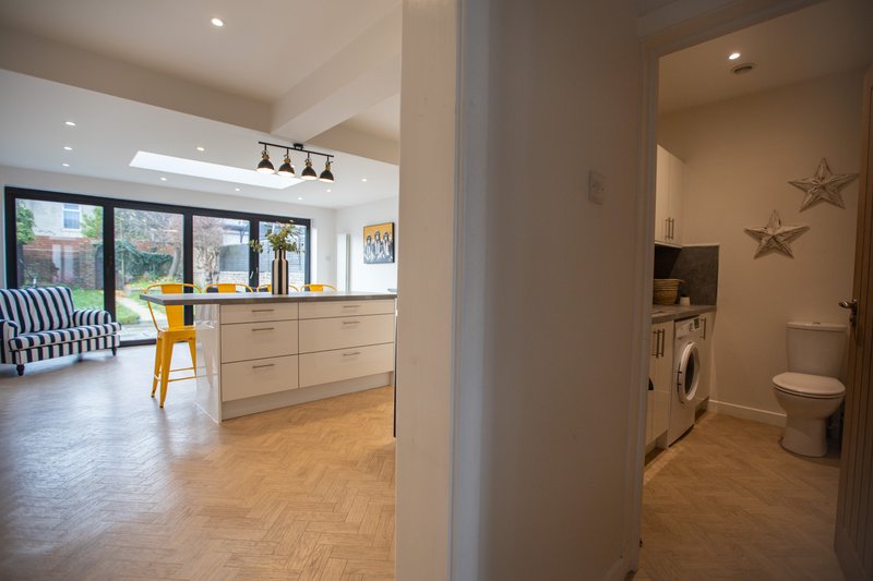 Open-plan kitchen with wooden cabinetry, pendant lights, and view into living area with seating