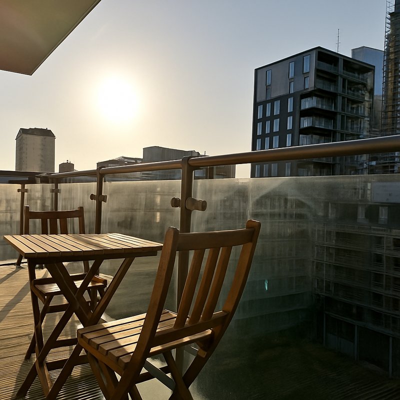 Wooden table and chairs on a sunny balcony with city skyline views
