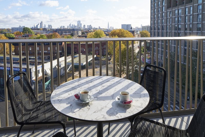 Balcony with round table, two chairs, and city skyline view in background
