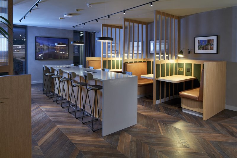 Modern open-plan kitchen and dining area with island seating, wooden cabinetry, and herringbone flooring