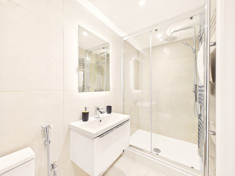 Modern white bathroom with vanity sink, mirror, shower enclosure and heated towel rail