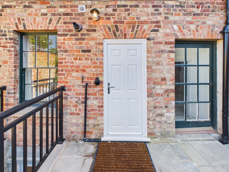 Brick building exterior with white door, black-framed windows and metal railing