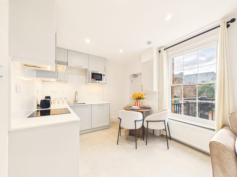 Modern open-plan kitchen and dining area with white cabinetry, island counter, and large windows overlooking landscape
