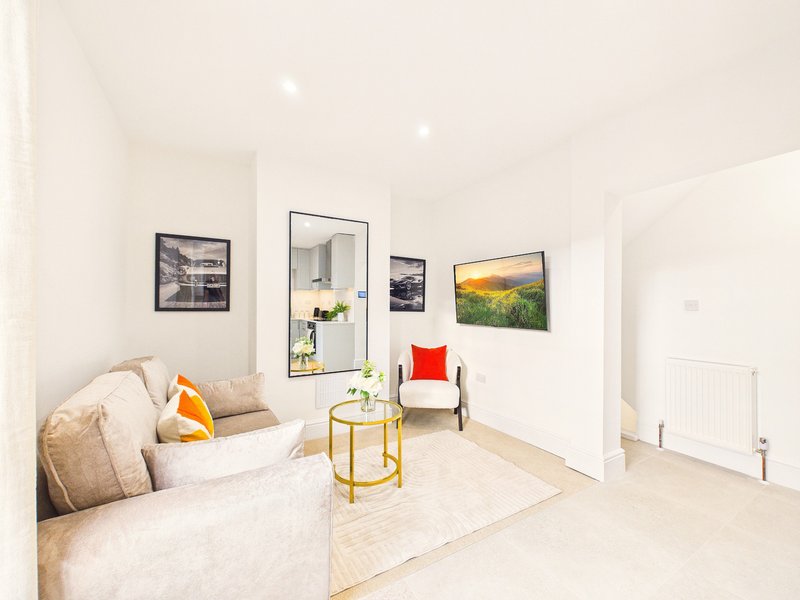 Bright modern bedroom with double bed, armchair, framed wall art and gold side table