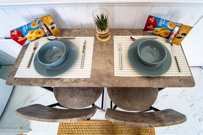 Overhead view of dining table set for two with place settings, bowls, and packaged food items
