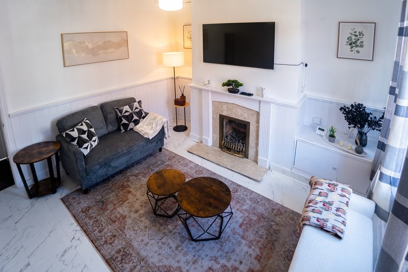 Living room with dark sofa, fireplace, TV, wooden coffee table and patterned rug