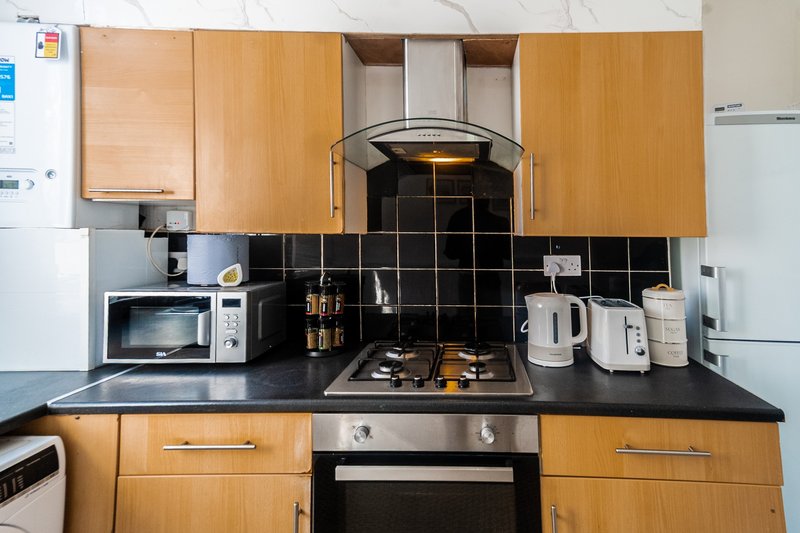 Modern kitchen with wooden cabinets, black tile backsplash, stainless steel appliances and countertop