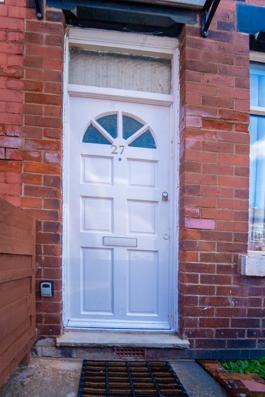 Red brick terraced house with white panelled front door and fanlight window
