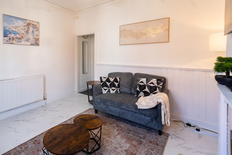 Bright living room with grey sofa, wooden coffee table, wall art and radiator