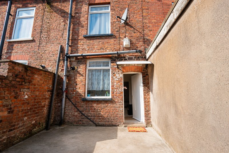 Brick terraced house exterior with paved courtyard entrance and white door