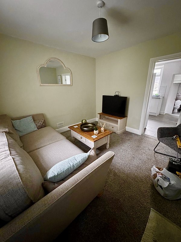 Bright living room with beige sofa, wooden coffee table, flat-screen TV, and pendant light