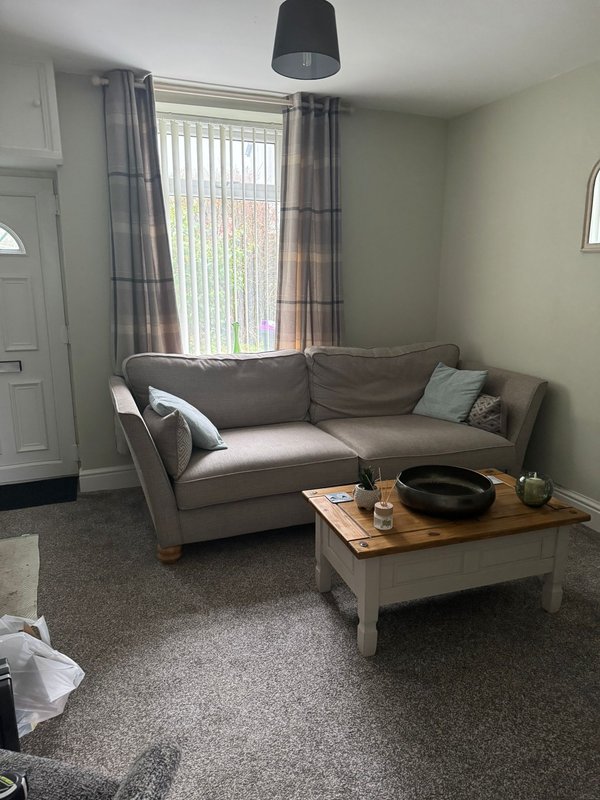 Living room with grey sofa, wooden coffee table, large window with curtains and pendant light