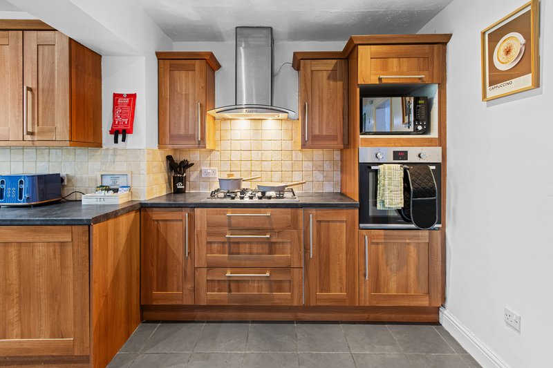 Modern kitchen with wooden cabinets, stainless steel cooker hood, and integrated appliances