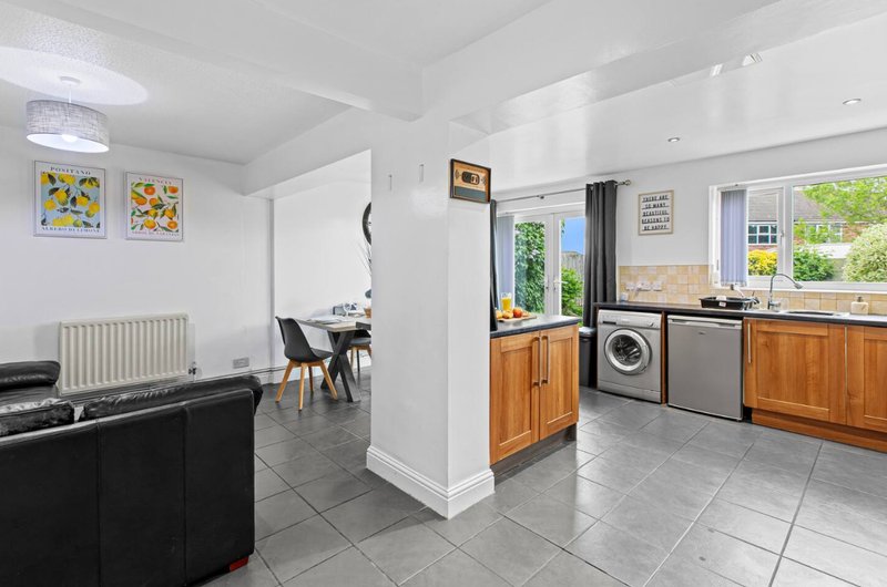 Open-plan kitchen and living area with wooden cabinetry, appliances, and seating
