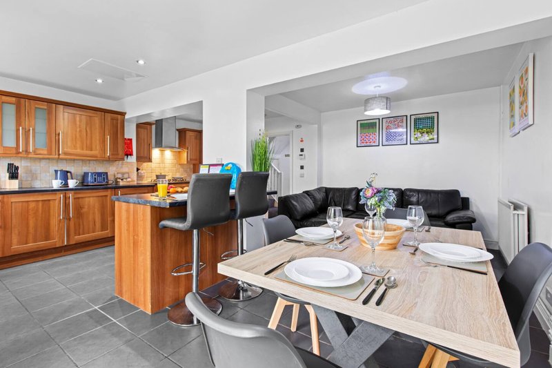 Open-plan kitchen and dining area with wooden cabinets, dining table, and black sofa