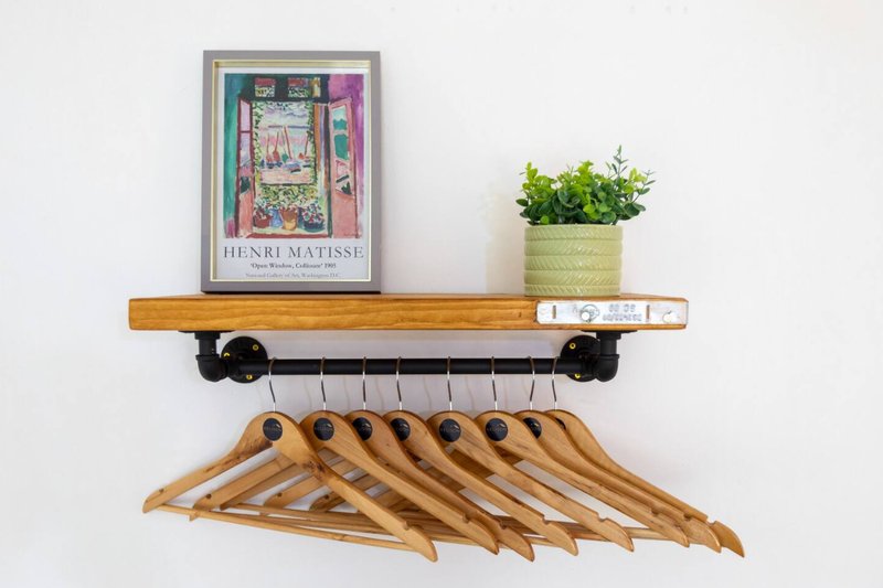 Wooden shelf with framed art print, potted plant, wooden hangers displayed below