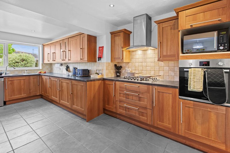 Modern kitchen with wooden cabinets, stainless steel appliances, and tiled flooring