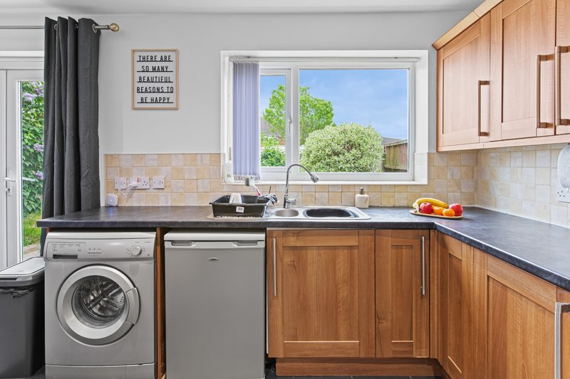 Modern kitchen with wooden cabinets, stainless steel appliances, and garden view through window