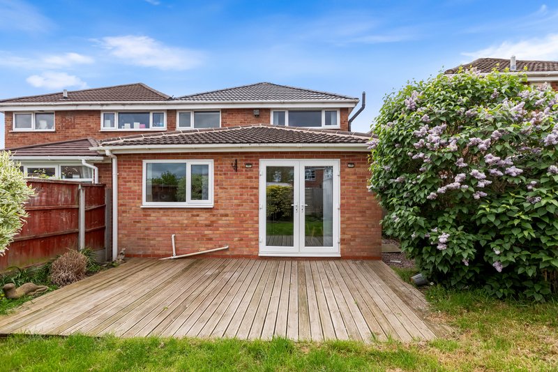 Brick house exterior with wooden deck, patio doors, and climbing ivy on side wall