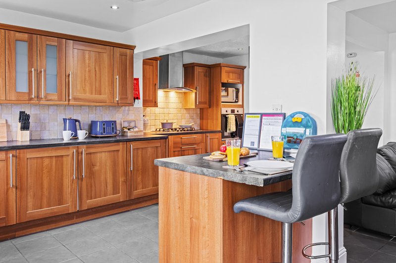 Modern kitchen with wooden cabinets, island seating, and open-plan dining area