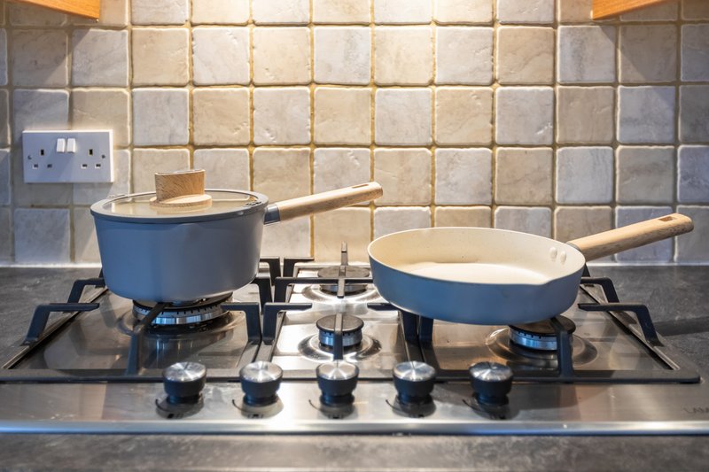 Kitchen stovetop with blue cookware and tile backsplash