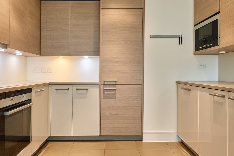Modern kitchen with light wood and cream cabinetry, built-in appliances, and tile flooring