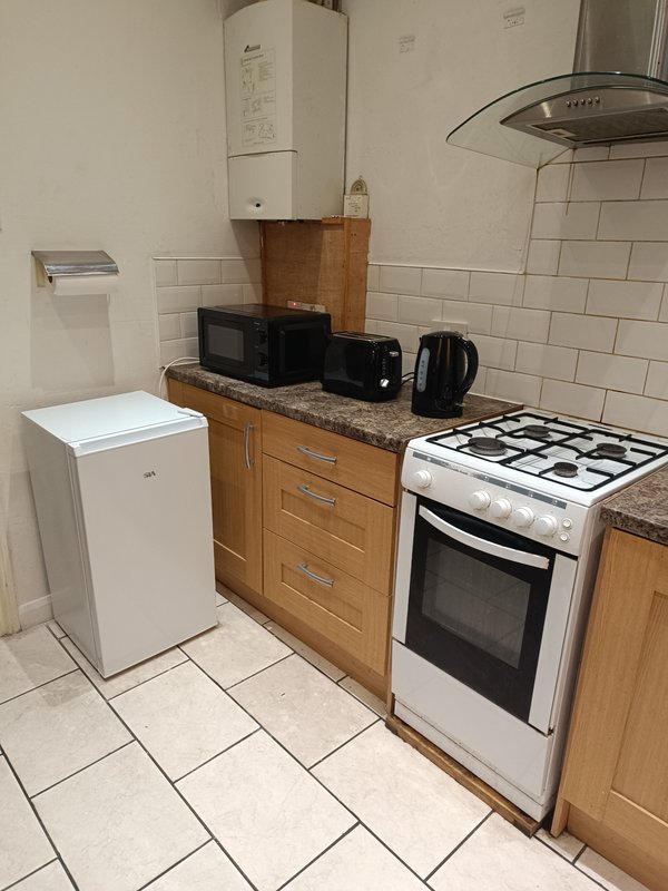 Compact kitchen with wooden cabinets, white appliances, gas cooker and tiled floor