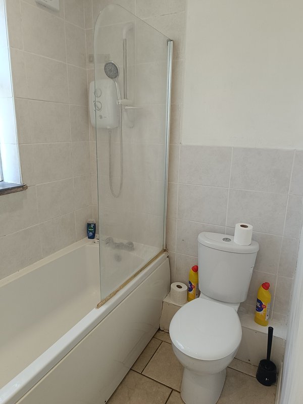 Bathroom with toilet, bathtub, shower enclosure and beige tile walls