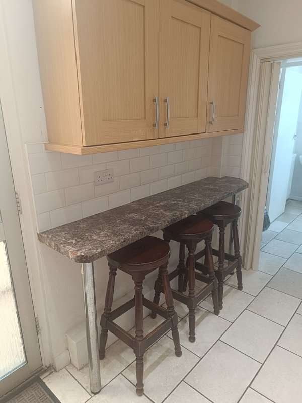 Kitchen breakfast bar with granite countertop, wooden cabinetry, and two bar stools