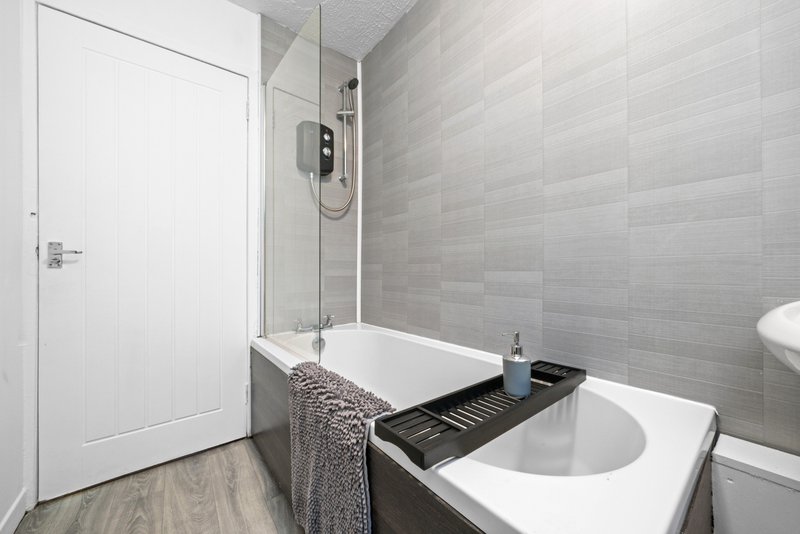 Modern bathroom with white subway tile walls, walk-in shower, toilet and sink vanity