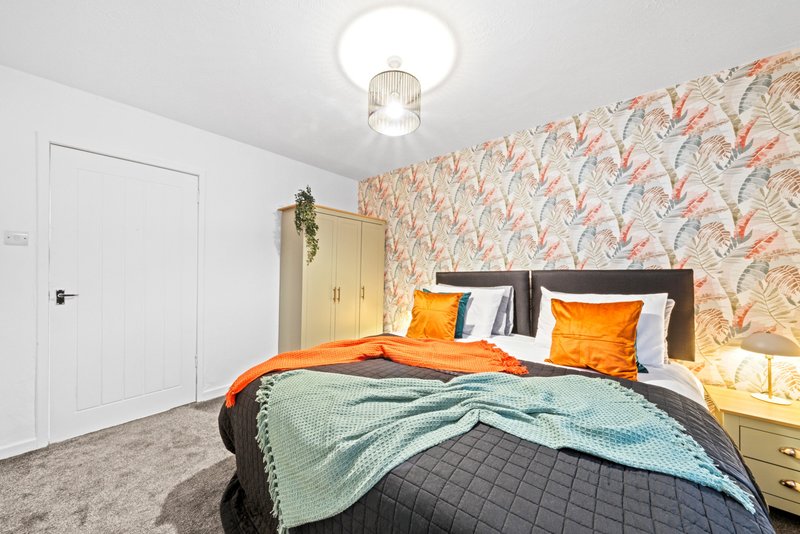 Modern bedroom with double bed, patterned wallpaper, wooden wardrobe and ceiling light
