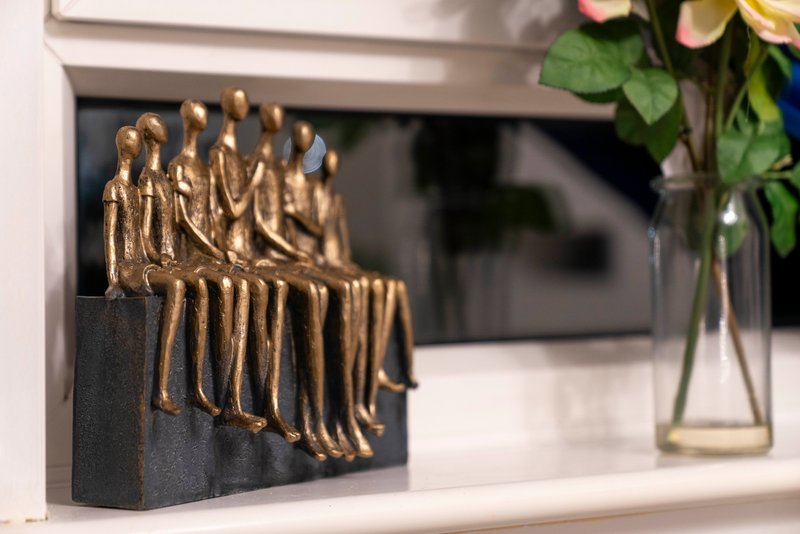 Decorative gold figurine sculpture on black base, shelf with flowers in vase