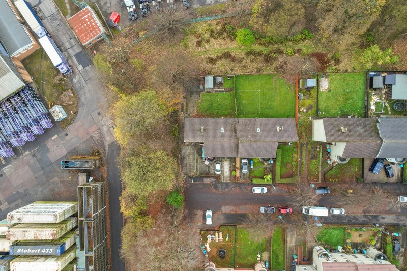 Aerial view of residential street with terraced houses, gardens and parked cars