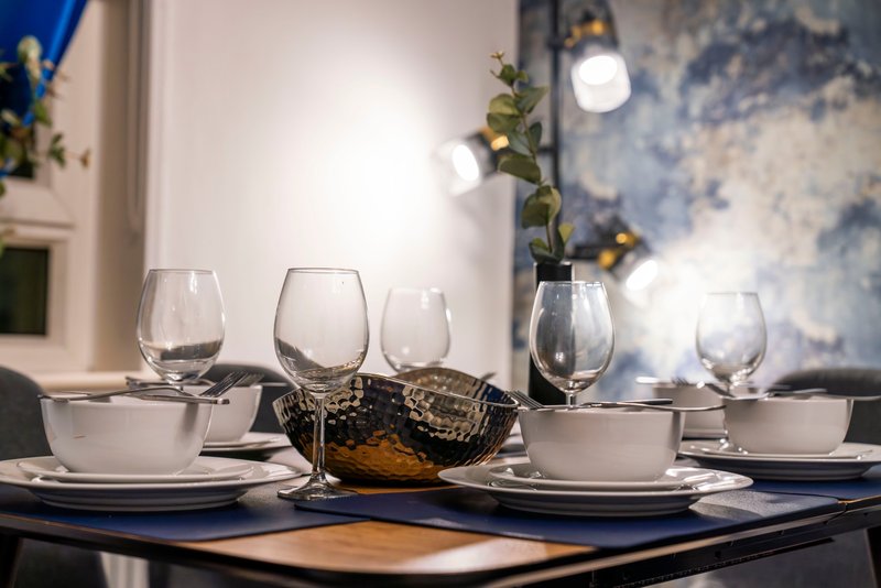 Formal dining table set with white plates, glasses, and floral centerpiece