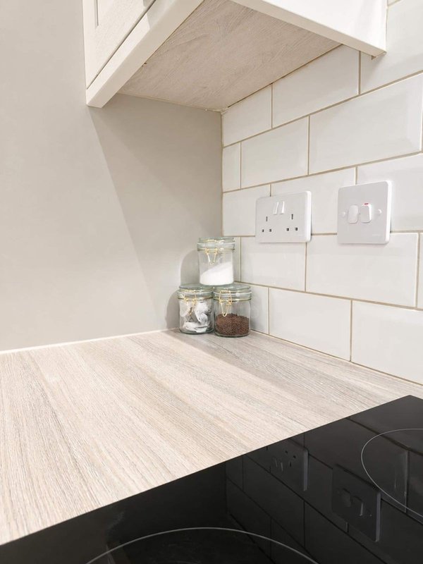 Modern kitchen counter with white subway tile backsplash, shelf above, and storage jars