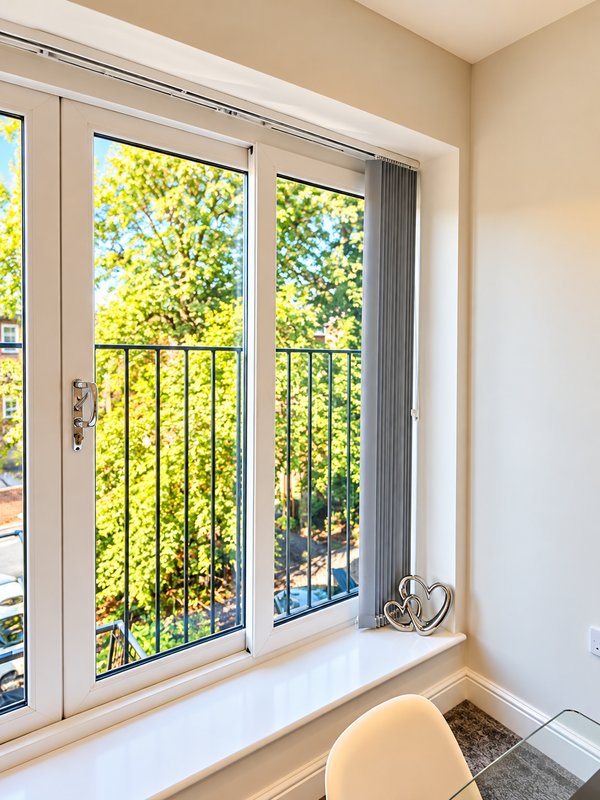 Bright window seat with dual glass doors, metal railings, and view of green foliage outside