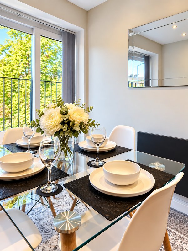 Modern dining room with black table, white chairs, yellow flowers, and balcony view