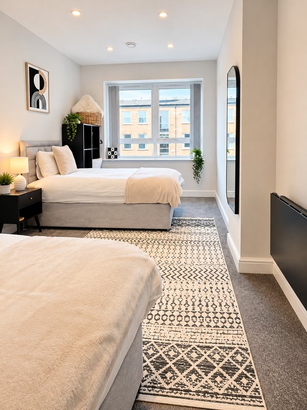 Modern bedroom with two beds, window seat, potted plants and recessed lighting
