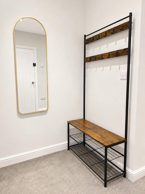 Entryway with arched mirror, wooden and metal coat rack with bench seating