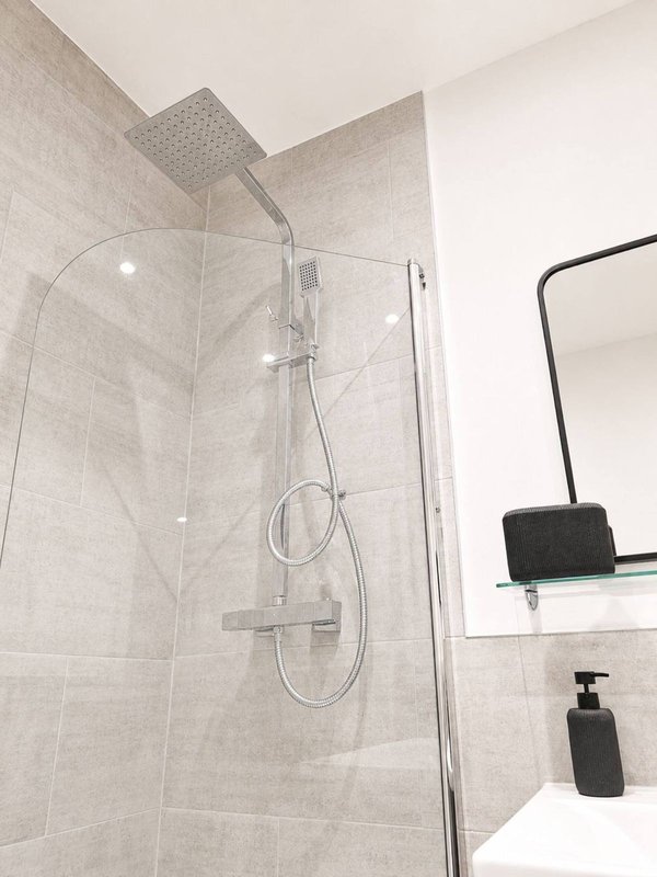 Modern bathroom with walk-in shower, rainfall showerhead, glass enclosure and neutral tiling