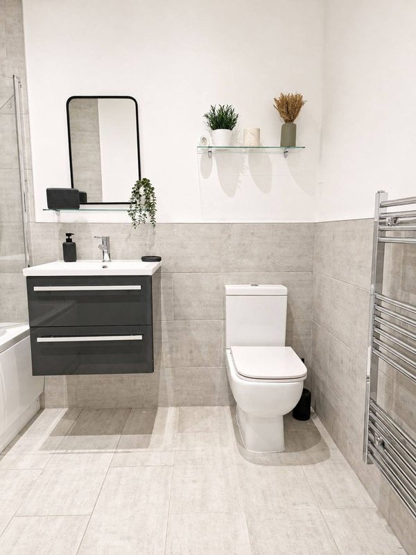 Modern bathroom with vanity unit, mirror, toilet, shelf with plants and towel rail