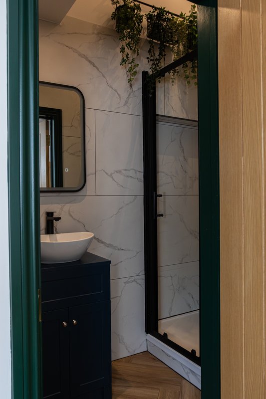 Modern bathroom with marble-tiled shower enclosure, vessel sink and green frame door
