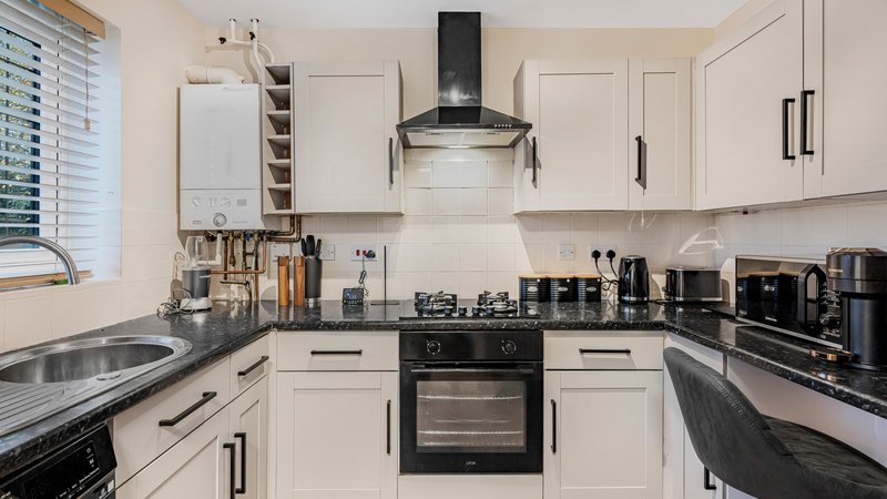 Modern white kitchen with black gas range, stainless steel appliances and countertops