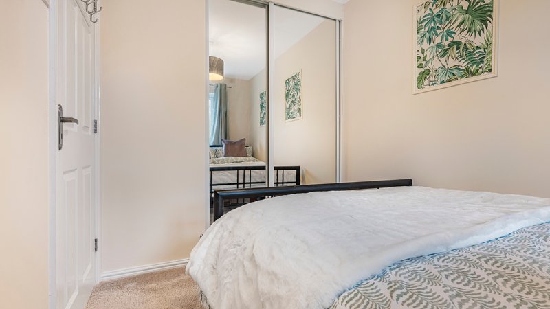 Bright bedroom with double bed, large mirror wardrobe, and cream-colored walls
