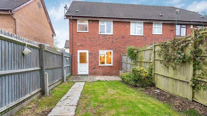 Brick semi-detached house rear garden with patio door, lawn and wooden fencing