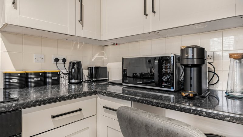 Modern kitchen with white cabinetry, black granite countertop and stainless steel appliances