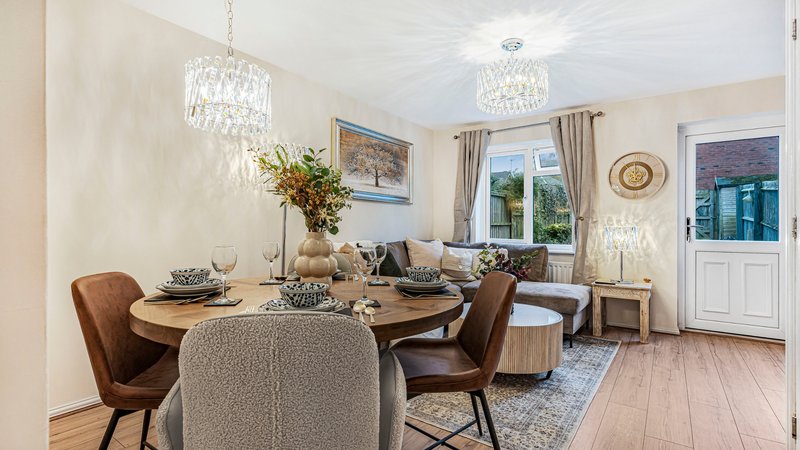 Bright dining room with round table, brown leather chairs, crystal chandelier and garden view