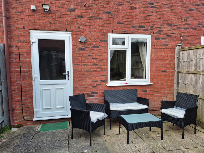 Red brick exterior with white door, window, and black wicker seating area on patio