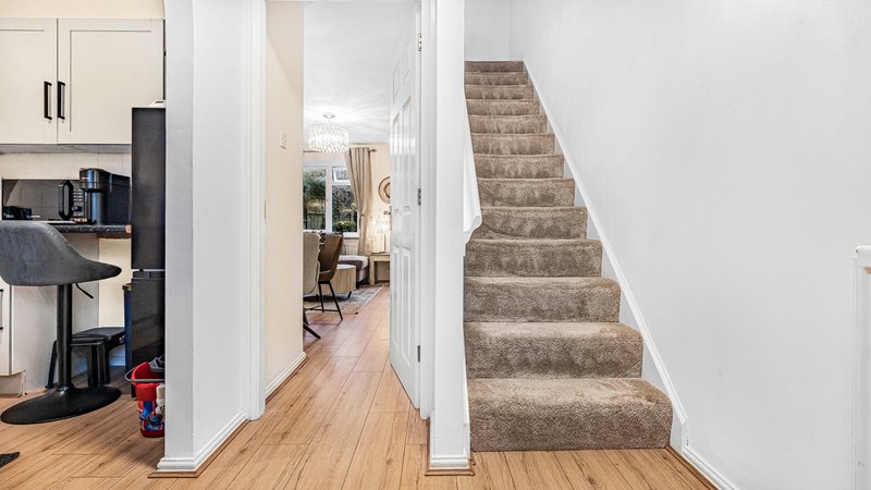 Open-plan kitchen and hallway with wooden flooring and staircase to upper level